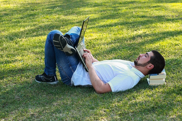 cours à distance lahochi homme allongé avec ordinateur sur herbe